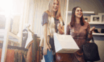 Two women enjoy shopping for clothing at different boutiques. 
