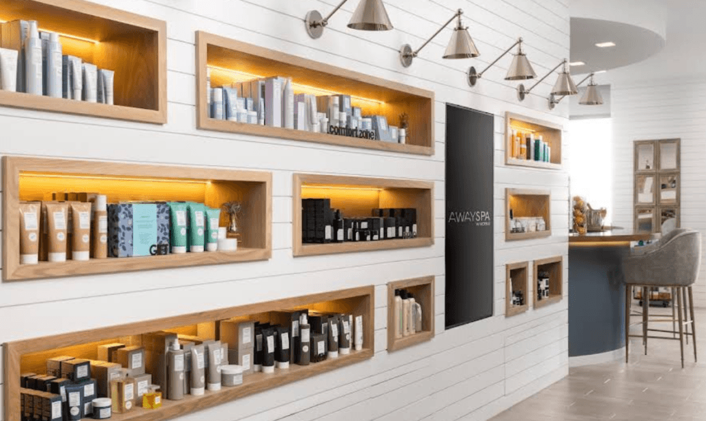 Retail wall at AWAY Spa at W Scottsdale featuring illuminated shelves filled with skincare and beauty products.