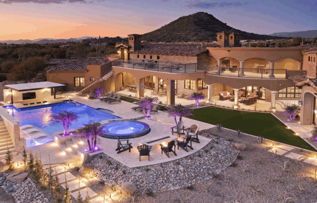 A desert vacation home at night with a glowing pool.