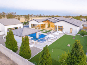 The estate offers a backyard with a pool, swim-up bar, putting green, and sports court.