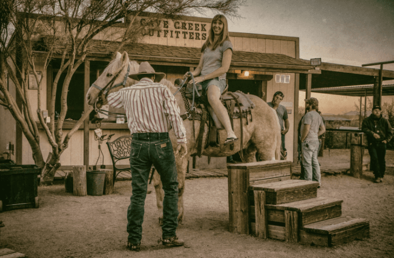 A woman on a horse in an old west town.
