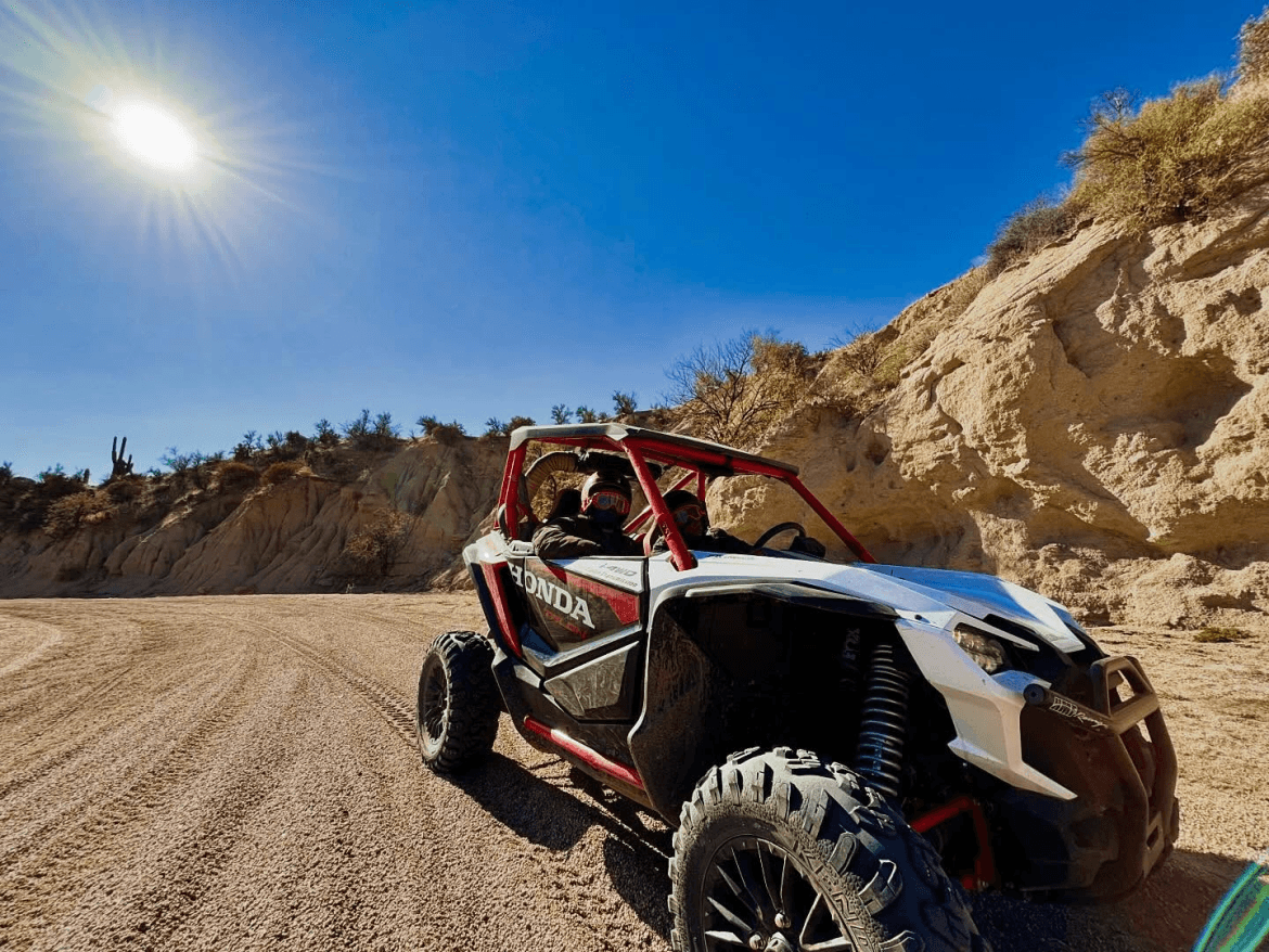 A white and red ATV on a dirt road in the desert.