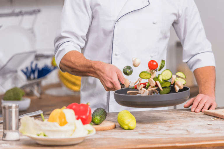 Chef tossing fresh vegetables in a pan in a kitchen.