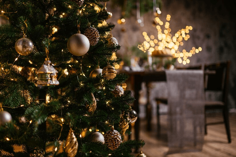 Close-up of a decorated Christmas tree with a festive dining table in the background.