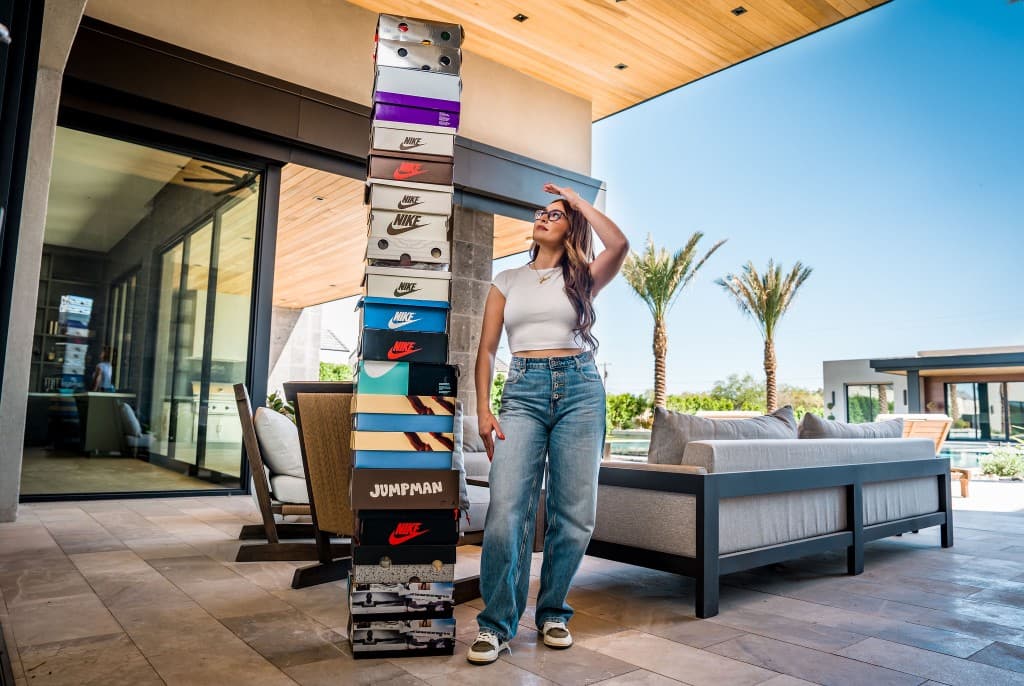 Laura Laces next to a tall stack of sneaker boxes on a patio
