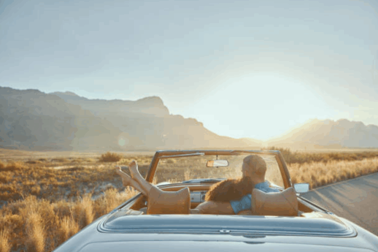Couple relaxing in a convertible at sunset on a scenic mountain road.