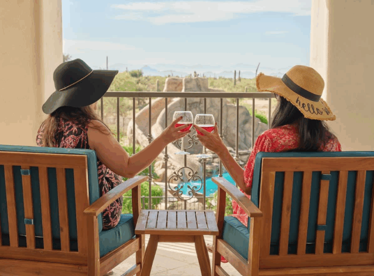An image of two women drinking wine on a porch balcony.