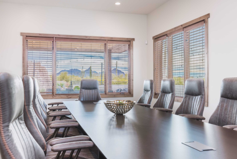 A larg conference desk with surrounding chairs in a luxury rental.