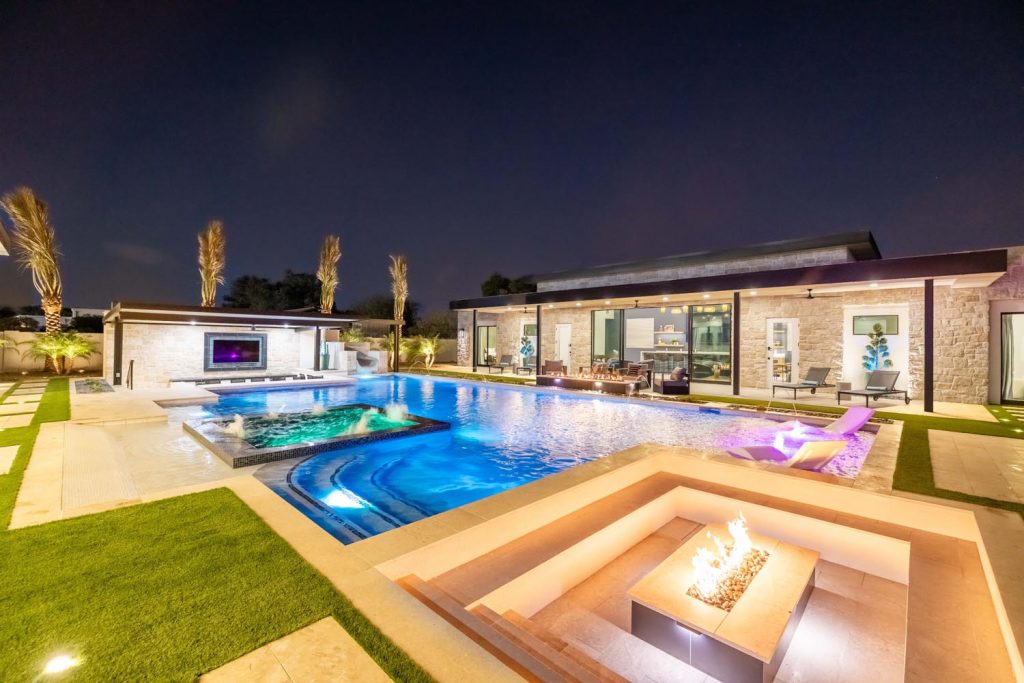 A vacation rental perfect for a destination wedding in Scottsdale, featuring a pool and hot tub at night.