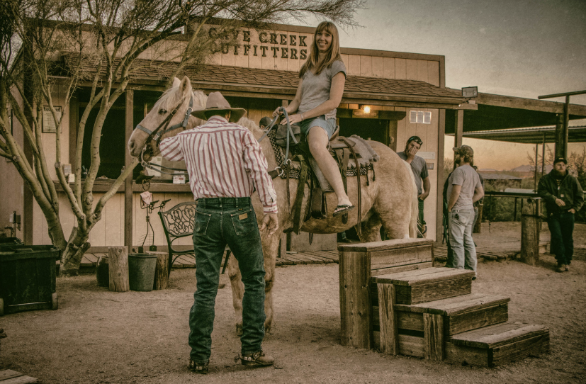 A woman on a horse in an old west town. 