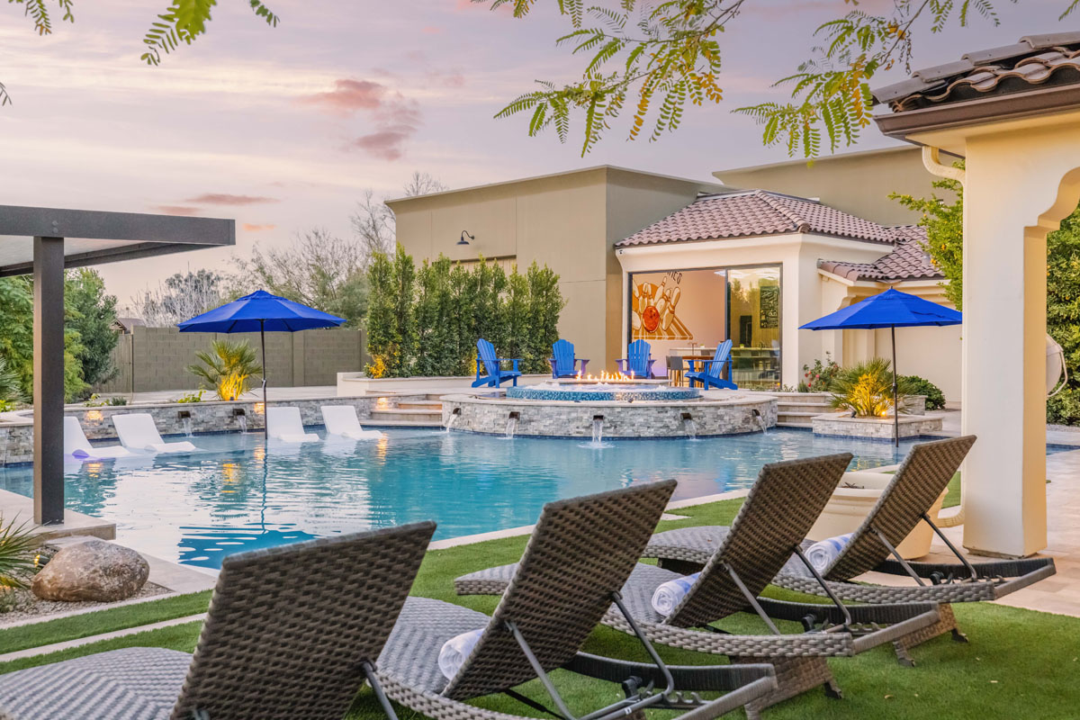 A luxury mansion rental with pool chairs and pool. 