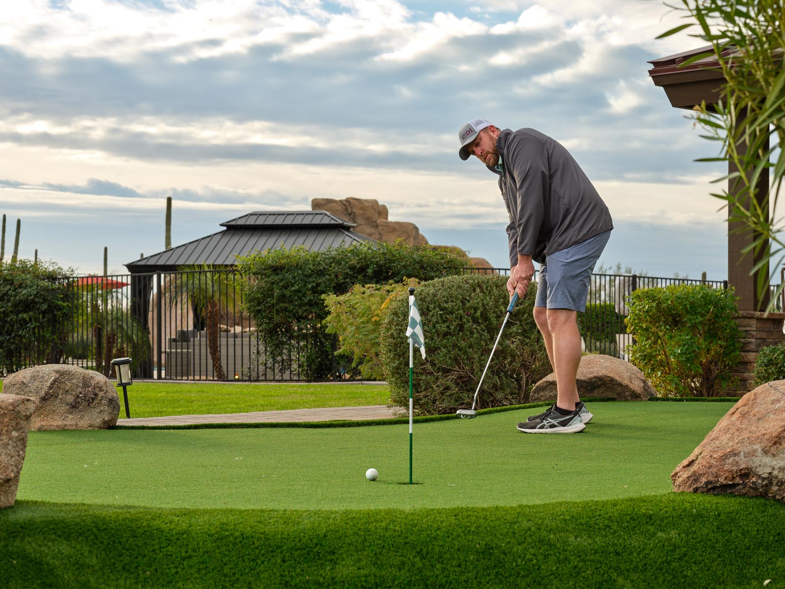 A man putts the golf ball into the hole on a putting green.