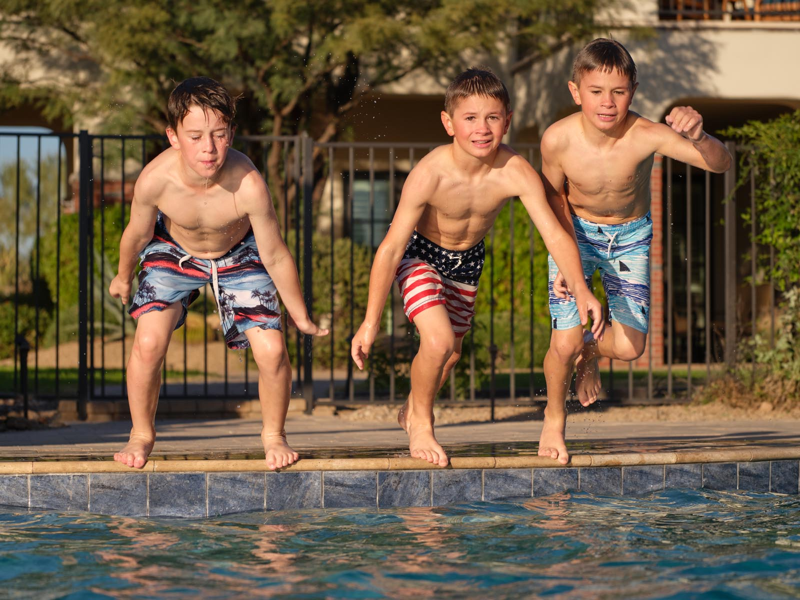 An image of three boys jumping into a HÓZHÓ Scottsdale pool. 
