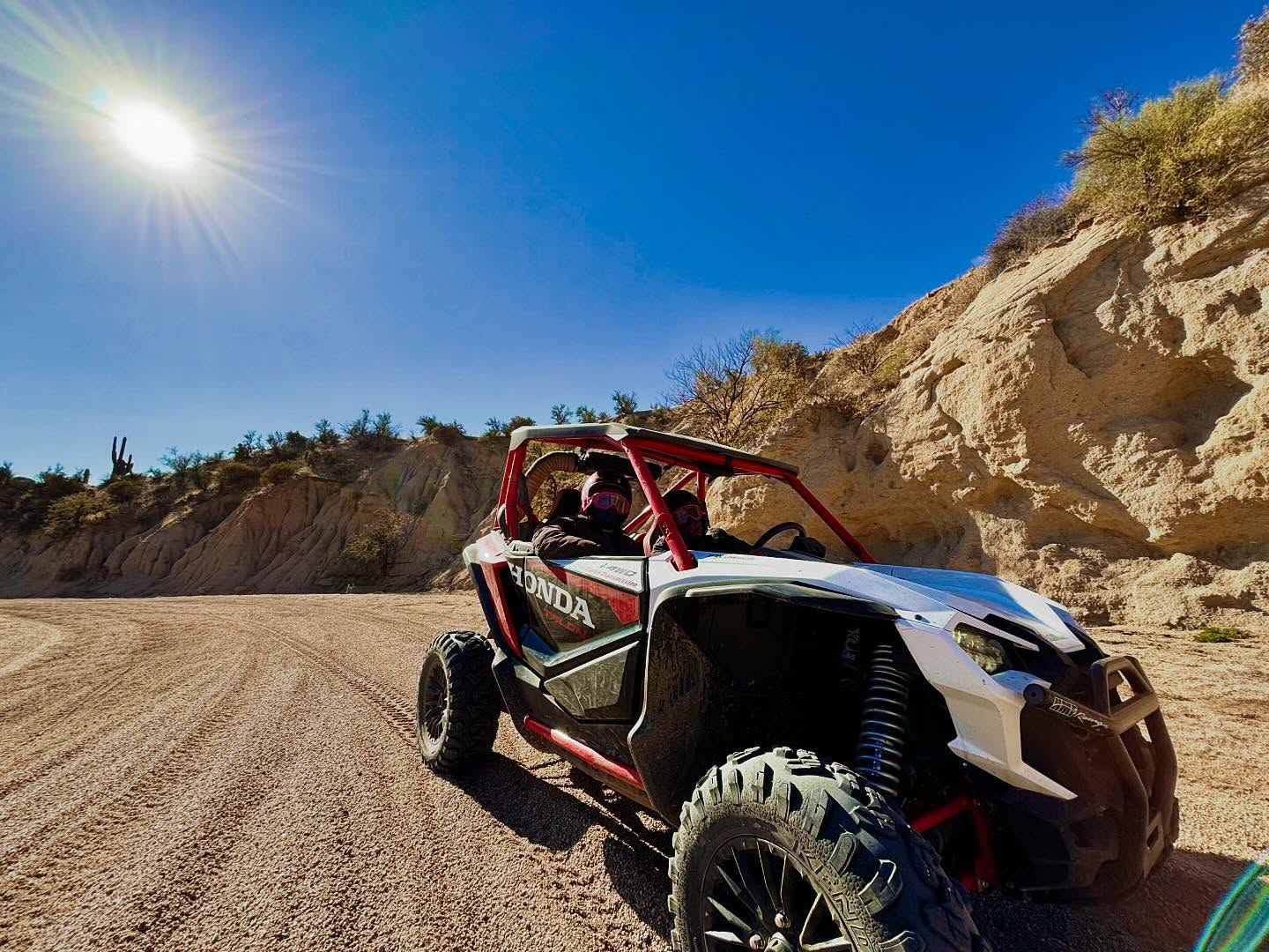 A white and red ATV on a dirt road in the desert. 