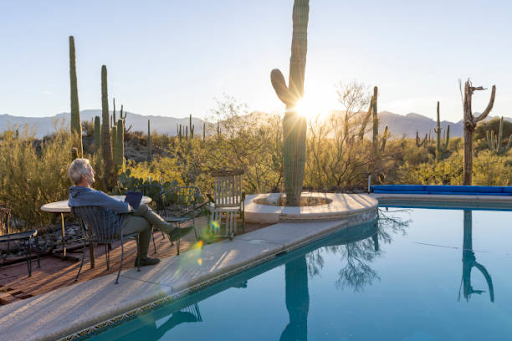 An image of a man relaxing outside in the desert near a pool