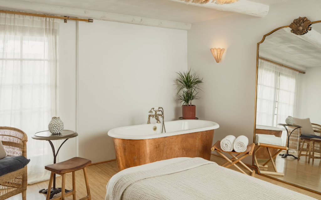 A serene treatment room at La Vidorra Spa at The Scott features a copper soaking tub, soft natural light, and a cozy massage table.