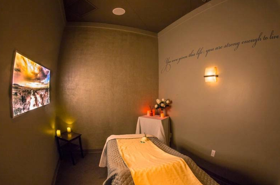 A cozy massage room at New Serenity Spa featuring warm lighting, candles, and a peaceful treatment table.