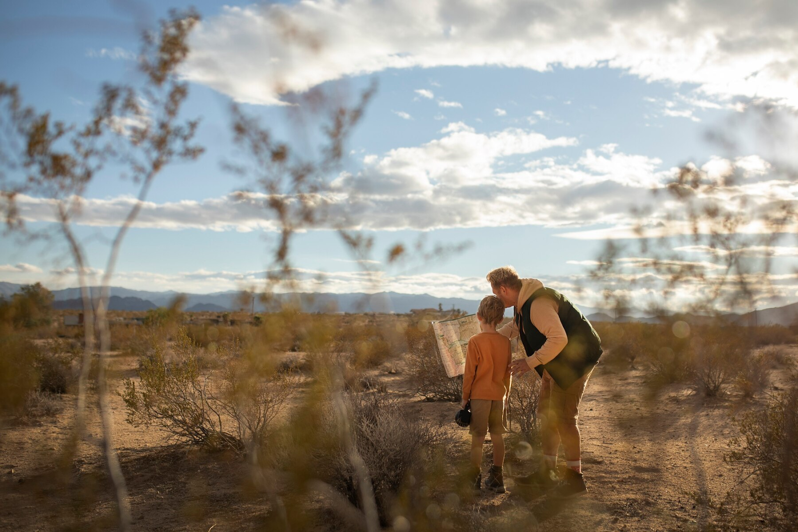 A father and son look at a map in the desert. 