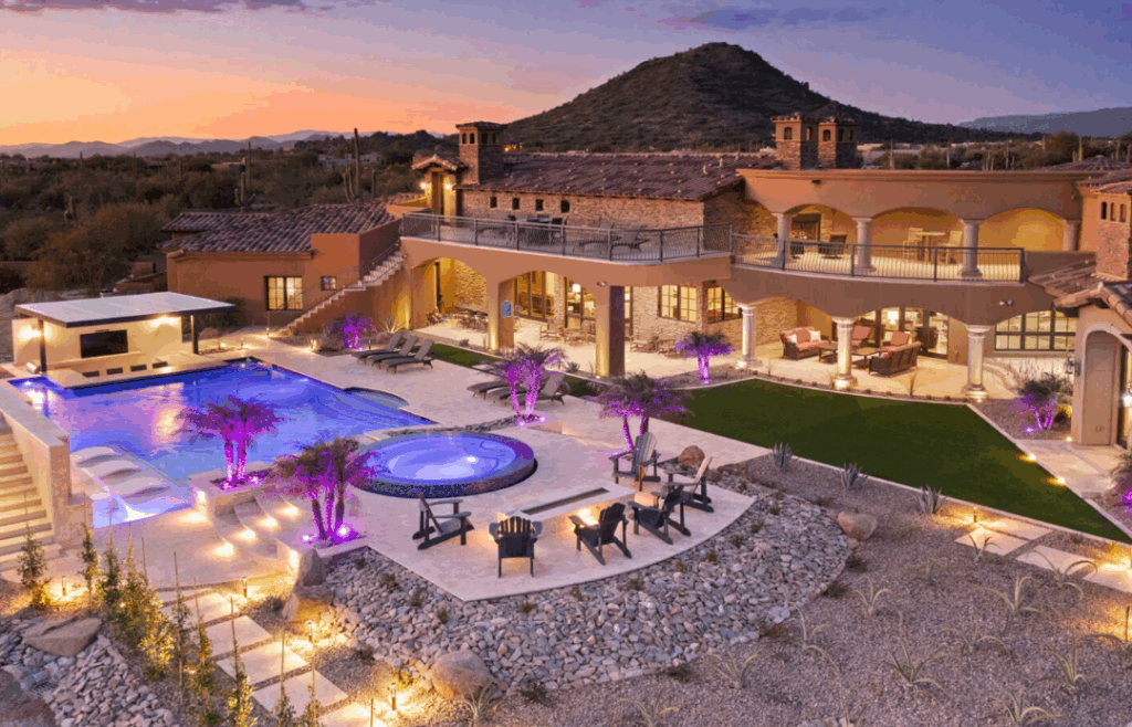 A desert vacation home at night with a glowing pool.