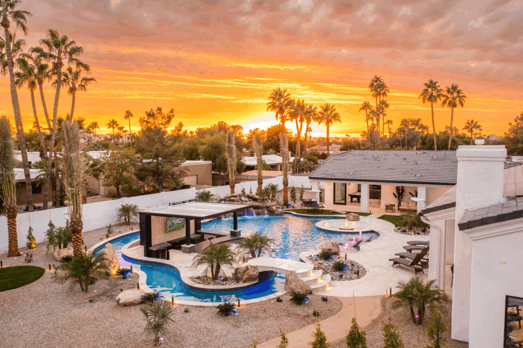 A sunset view of a vacation rental with a lazy river pool in a desert oasis. 