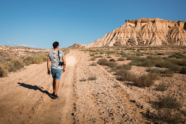 Young man with a camera in Bardenas Reales desert, Navarra, Basque Country.